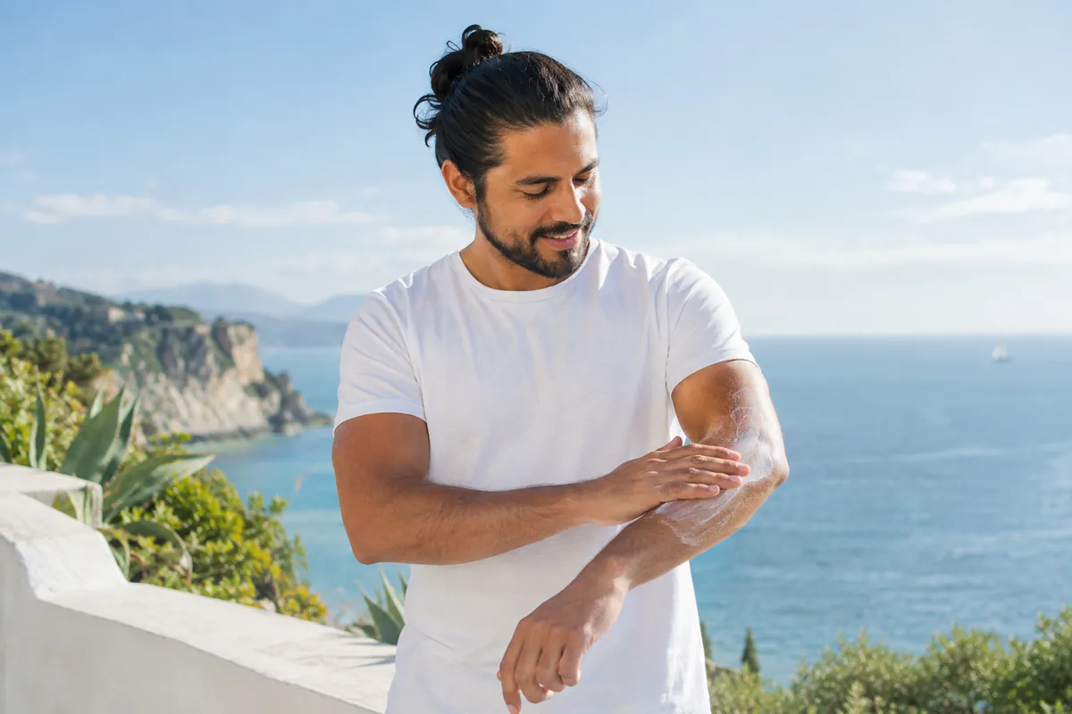 Person applying sunscreen to their arm on a sunny day